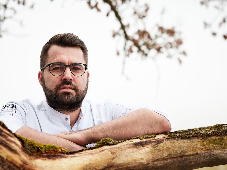 Der Sternekoch Andreas Widmann kombiniert Techniken aus Skandinavien und Fernost. Portraitfoto von Andi Widmann draußen im Wald